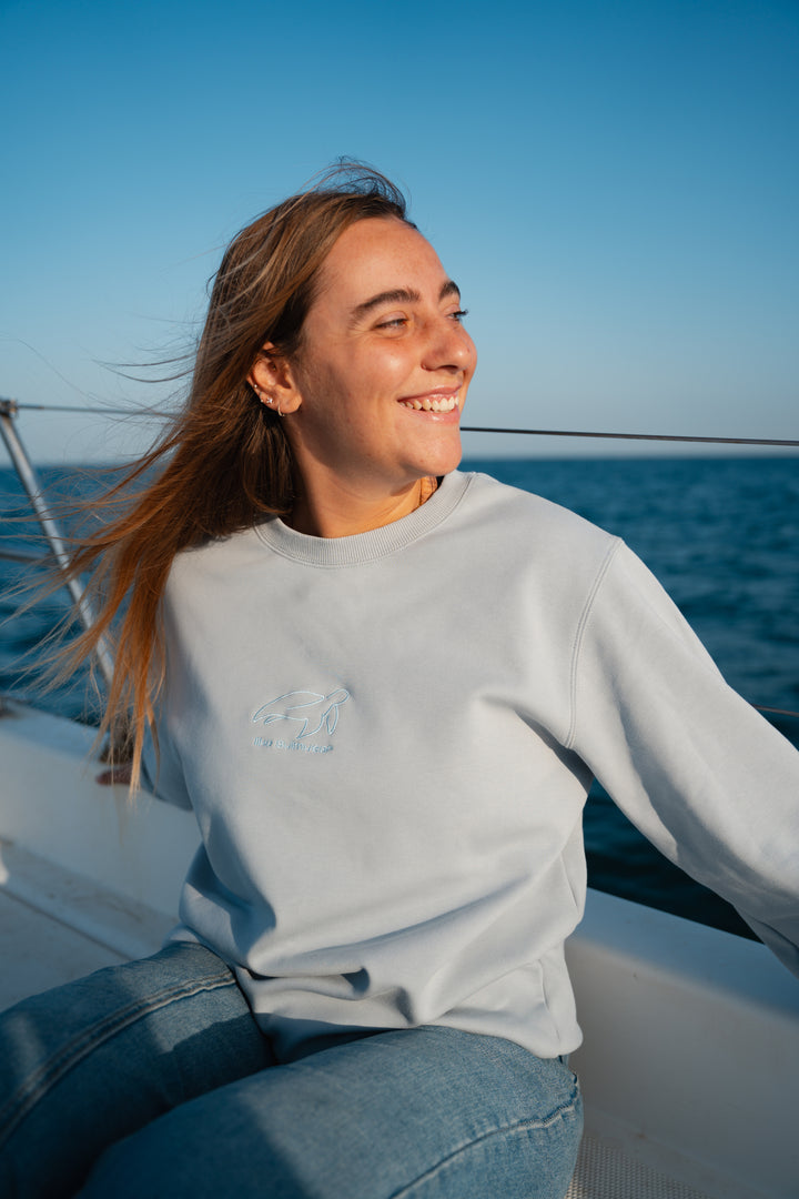 סוויטשירט אפור בהיר עם לוגו וטקסט על רקע נקי – פריט שמשדר מודרניות, נוחות וסטייל דיסקרטי, בדיוק כמו כל פריט ב-Lika Swimwear שמביא איכות וייחודיות לכל לוק יומיומי.