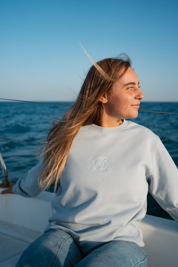 סוויטשירט אפור בהיר עם לוגו וטקסט על רקע נקי – פריט שמשדר מודרניות, נוחות וסטייל דיסקרטי, בדיוק כמו כל פריט ב-Lika Swimwear שמביא איכות וייחודיות לכל לוק יומיומי.