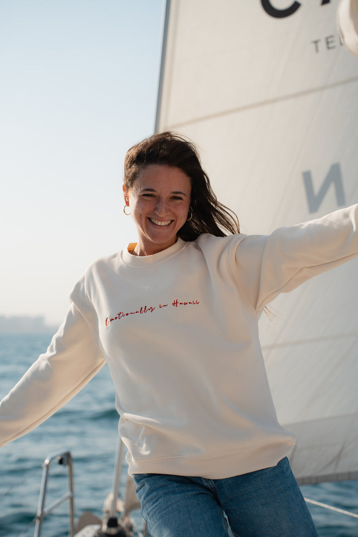 אישה על יאכטה לובשת סוויטשירט לבן עם טקסט – מראה שמשדר קלילות, חופש וסטייל ייחודי, בדיוק כמו כל פריט ב-Lika Swimwear שמלווה אותך ברגעים המיוחדים שלך על המים והחוף.